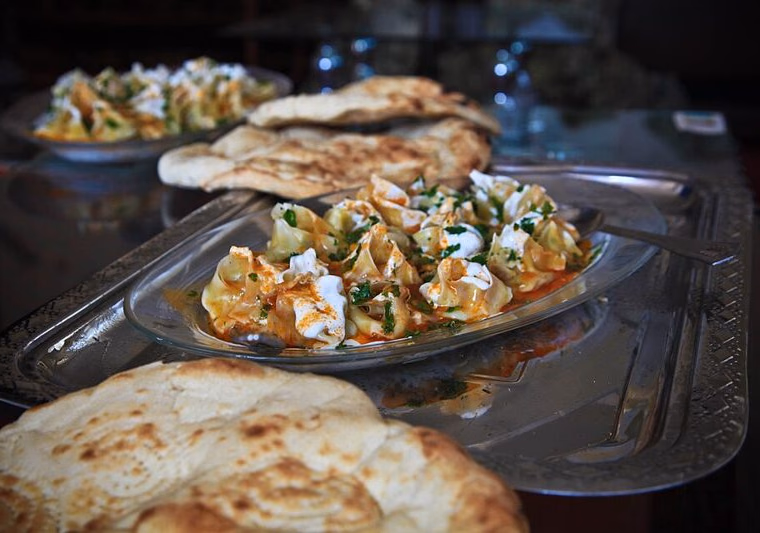 Afghan mantu with yoghurt and tomato sauce, with naan