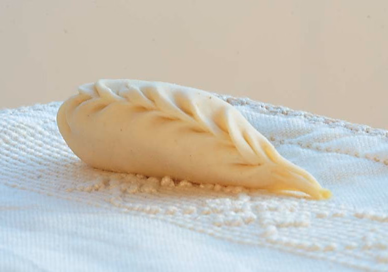 A single culurgione with its braided wheat-ear seam