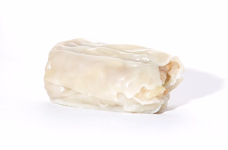 Single steamed dim sim on a white background; thick wrapper, open-top gathered fold. Cooked.
