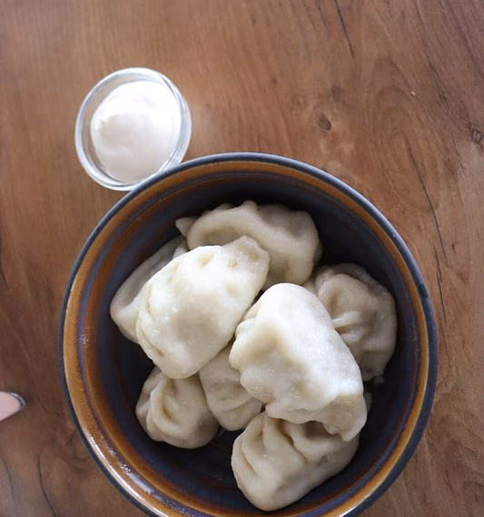 Boiled Kalmyk börg in a bowl with sour cream