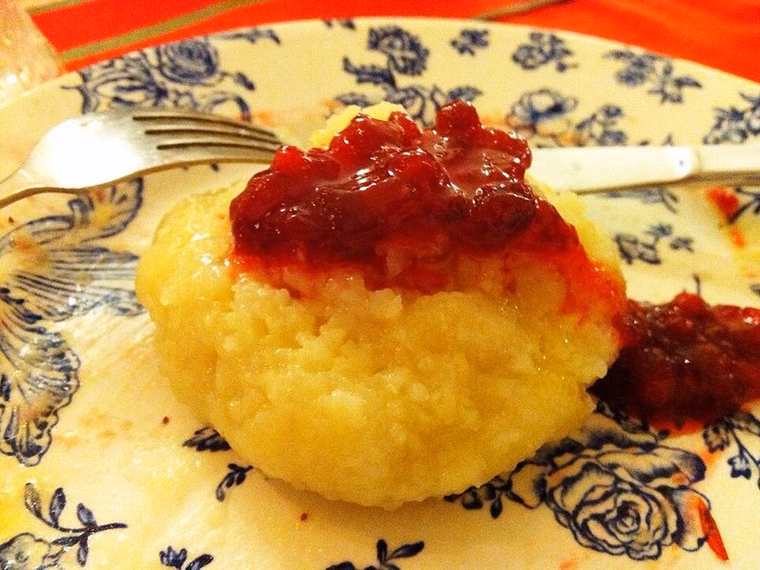 Homemade palt (fläskpalt) on a plate with lingonberry jam and butter. Round flattened potato dumpling, cooked.