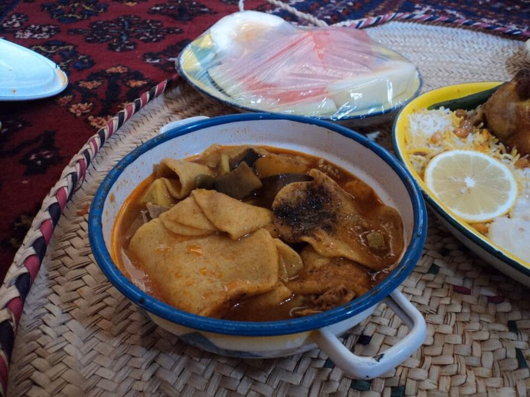 Saudi matazeez dough discs in a tomato and eggplant stew