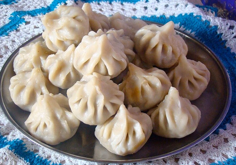 Steamed rice-flour ukadiche modak on a plate; pointed top with vertical pleats, clearly visible. Cooked.