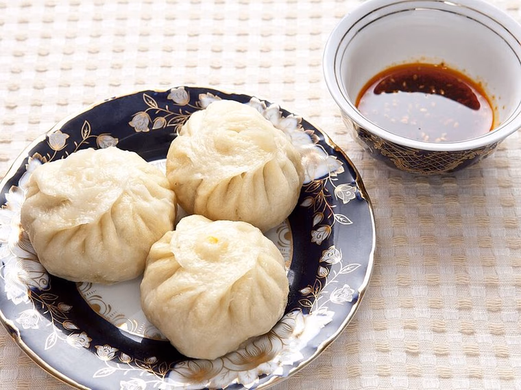 Steamed Uyghur manta, one cut open to show the minced filling; pleated top visible. Cooked.
